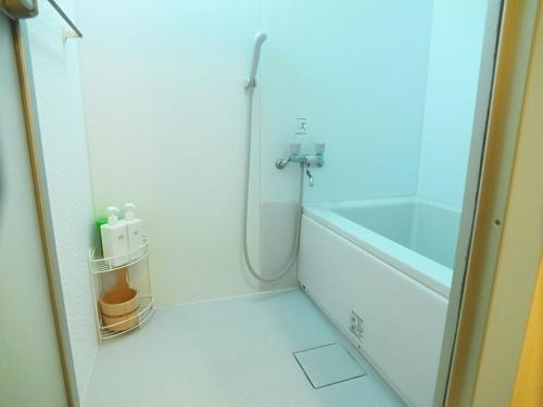 uma casa de banho com um chuveiro, uma banheira e um lavatório. em Asayake em Tóquio