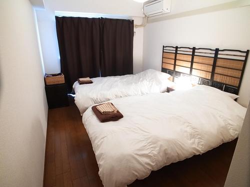 two beds in a room with white sheets at Asayake in Tokyo