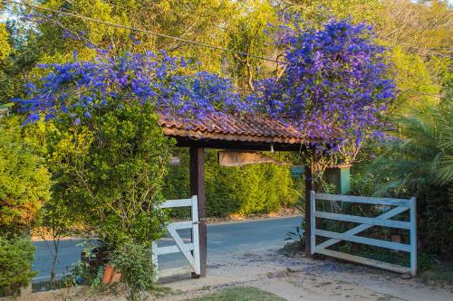 a gate with purple flowers and a white fence at Pousada Remanso do Rio Preto in Visconde De Maua