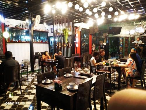 a group of people sitting at tables in a restaurant at Grand Pruksa Siri Apartment in Sara Buri