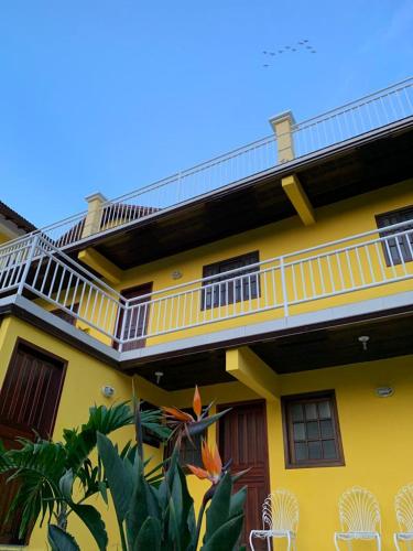 a yellow building with a balcony and chairs at Luxor Flat`s in Miguel Pereira