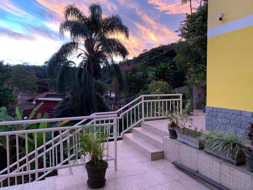 a balcony with stairs and a palm tree with a sunset at Luxor Flat`s in Miguel Pereira