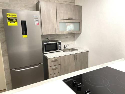 a kitchen with a refrigerator and a sink and a microwave at California Apartments in Yabucoa