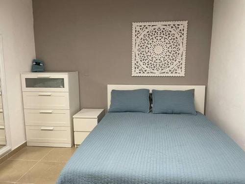 a bedroom with a blue bed and a dresser at California Apartments in Yabucoa