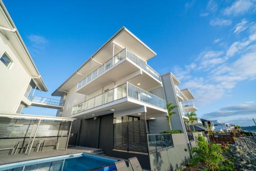 a house with a swimming pool in front of it at Harbour Cove in Airlie Beach