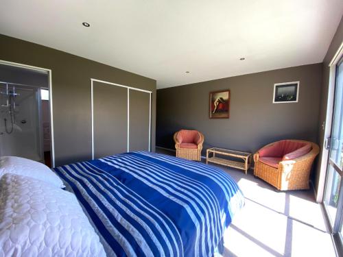 ein Schlafzimmer mit einem Bett und zwei Stühlen in der Unterkunft 4 Tarndale Place in Hanmer Springs