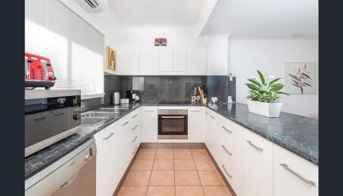 a kitchen with white cabinets and a black counter top at Entire 2 bedroom townhouse - Four Mile Beach Escapes - your home away from home in Port Douglas