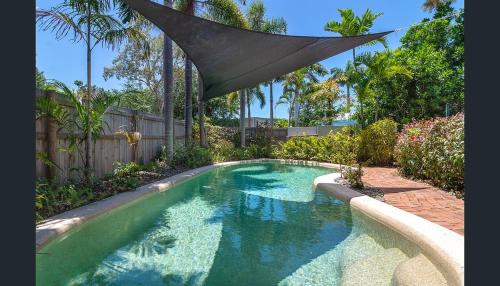 a swimming pool in a backyard with an umbrella over it at Entire 2 bedroom townhouse - Four Mile Beach Escapes - your home away from home in Port Douglas