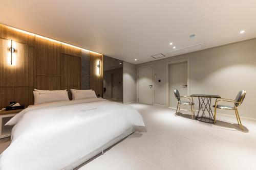 a bedroom with a large white bed and a table at Hotel Lium in Cheonan