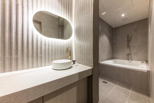 a bathroom with a sink and a tub and a mirror at Hotel Lium in Cheonan