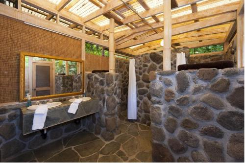 a stone bathroom with two sinks and a mirror at Waipio Valley Botanical Garden 