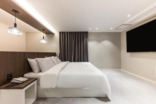 a bedroom with a large bed and a flat screen tv at Hotel Lium in Cheonan