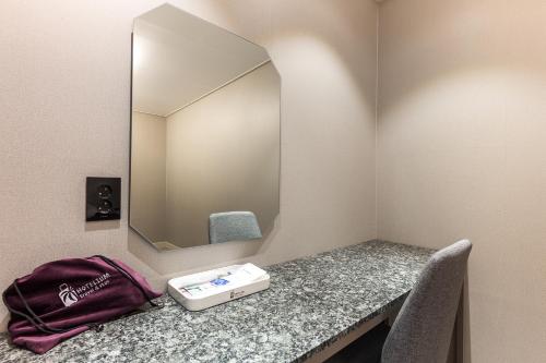 a vanity with a mirror and a bag on a counter at Hotel Lium in Cheonan