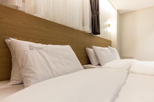 two white beds with white pillows in a room at Hotel Lium in Cheonan