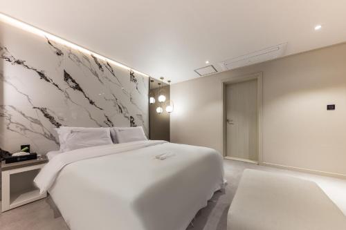 a white bedroom with a large bed and a wall at Hotel Lium in Cheonan