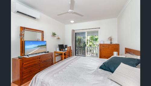 a bedroom with a bed and a television and a window at Entire 2 bedroom townhouse - Four Mile Beach Escapes - your home away from home in Port Douglas