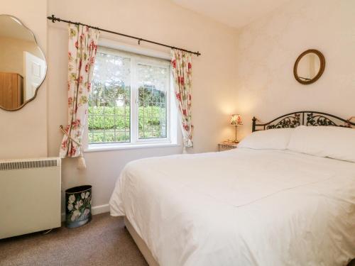 a bedroom with a white bed and a window at Claire's Cottage in Poughill