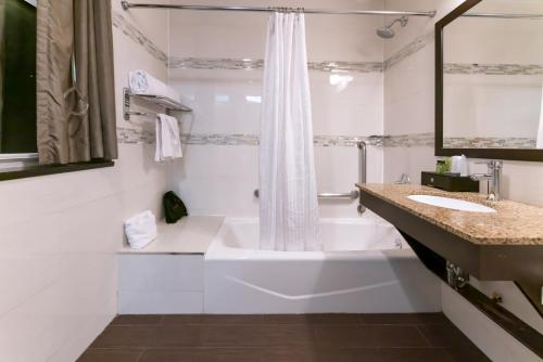 Baño blanco con bañera y lavamanos en Madison LES Hotel en Nueva York