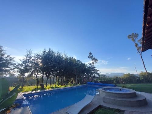 a swimming pool in a yard with trees in the background at Hostería Colibri Aeropuerto in Tababela
