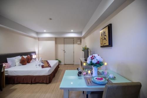 una habitación de hotel con una cama y una mesa con flores en Sky Place Srinakarin, en Bangkok