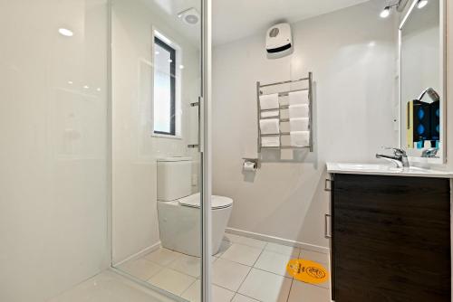 een badkamer met een douche, een toilet en een wastafel bij Riccarton Mall Motel in Christchurch