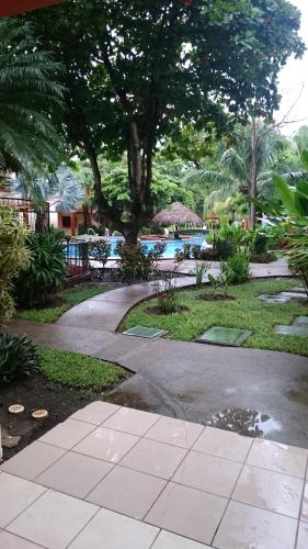 un passaggio che conduce a una piscina con un albero di Room in Condo - Nice condo to vacation in Playas del Coco a Coco