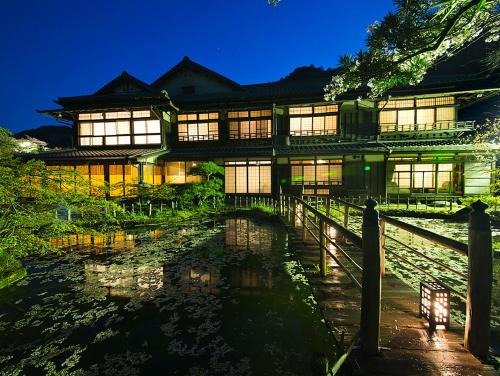an asian style building with a pond in front of it at Nanten-En in Kawachinagano