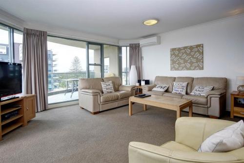 a living room with two couches and a tv at Sails Apartments in Forster