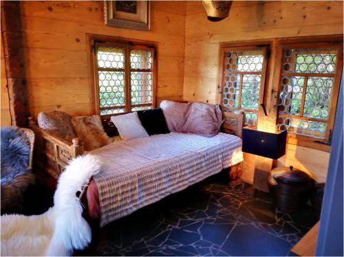 a bedroom with a couch and windows in a log cabin at Chalet with view of the mountains and the Thun lake in Sigriswil