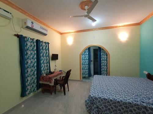 a bedroom with a bed and a table and a ceiling fan at Jerone's Home Stay in Majorda