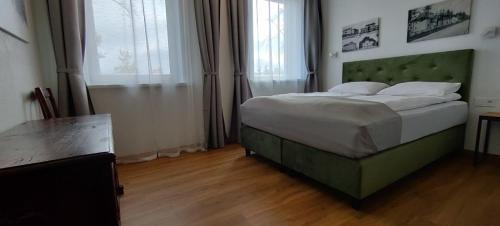 a bedroom with a bed with a green headboard at Exceptional Pogegen Apartment in Pagėgiai