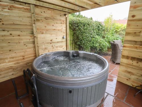 a hot tub in a backyard with a wooden wall at The Honey Pot in Chepstow