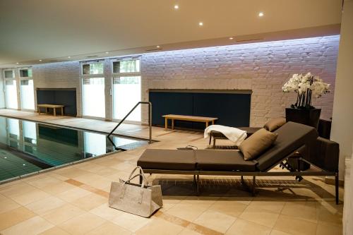 a living room with a couch and a swimming pool at Seehotel am Tankumsee in Isenbüttel