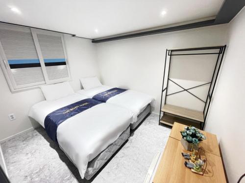 a bedroom with two beds and a table and a mirror at The Road Hotel in Seoul