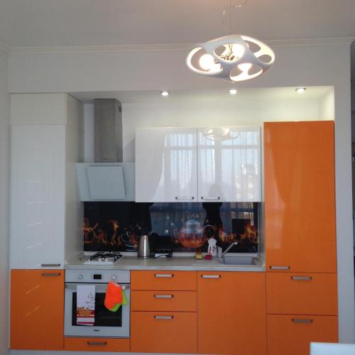 uma cozinha com armários laranja e um fogão em Sea Rapsody Apartment em Adler