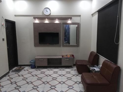 卡拉奇的住宿－Karachi Guest House，客厅配有电视、沙发和椅子