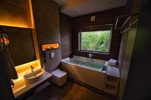 baño con bañera, lavabo y ventana en Jungle Bay Resorts & Spa, en Wayanad