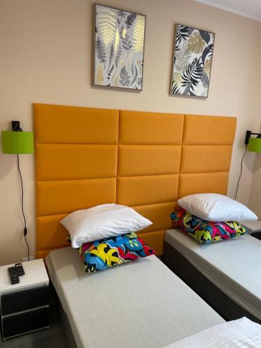 - une chambre avec deux lits et une grande tête de lit orange dans l'établissement Apartament Nad Nielbą, à Wągrowiec