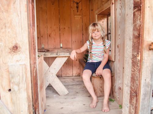a little girl sitting in a wooden cabin at Biobauernhof Stegerbauer in Maria Alm am Steinernen Meer