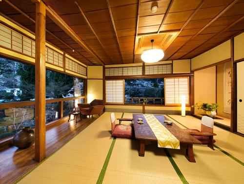 a living room with a table and chairs and windows at Nanten-En in Kawachinagano