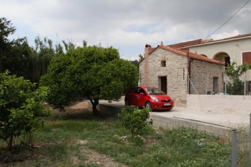 een rode auto geparkeerd voor een gebouw bij Irini’s house in Chios
