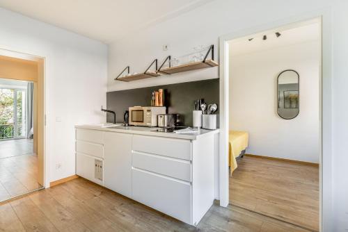 a white kitchen with a sink and a microwave at limehome Augsburg Pilgerhausstraße in Augsburg