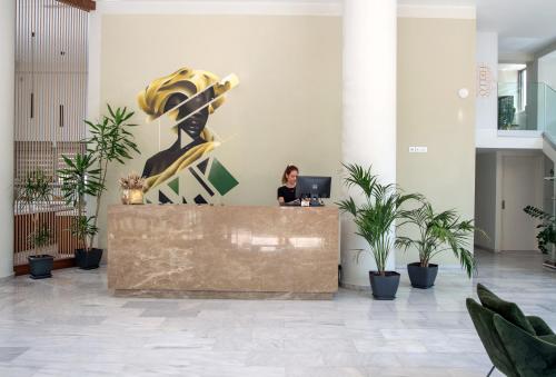 a woman sitting at a desk in a lobby at B4B Athens Signature Hotel in Athens