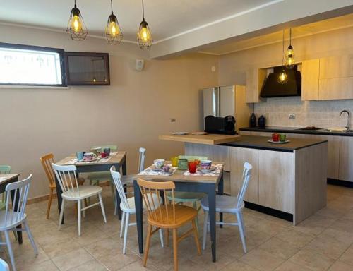 een keuken met 2 tafels en stoelen en een keuken met een aanrecht bij Albamaris Guest House in Botricello