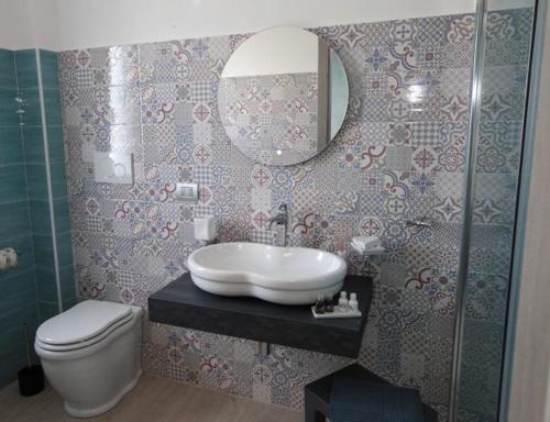 een badkamer met een wastafel, een toilet en een spiegel bij Albamaris Guest House in Botricello