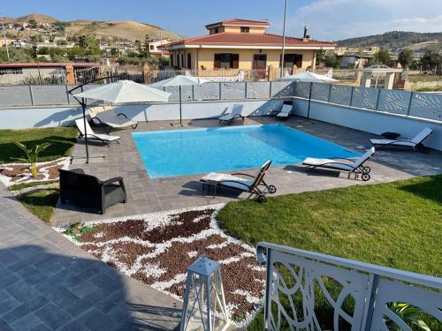 een zwembad met stoelen en een huis bij Albamaris Guest House in Botricello