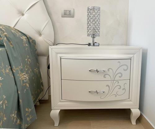 a white nightstand with a lamp on it next to a bed at Albamaris Guest House in Botricello
