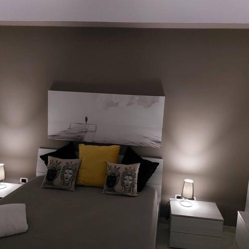 a bedroom with a bed with two tables and two lamps at Focu e Mari in Mascali