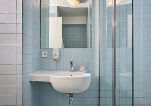 une salle de bain avec un lavabo et un miroir dans l'établissement Aparthotel Adagio Access Paris Bastille, à Paris