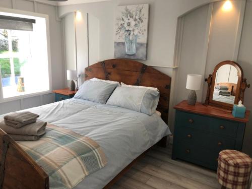 Schlafzimmer mit einem Bett mit einem Kopfteil aus Holz und einem Spiegel in der Unterkunft Bracken Cottage in Ballymartin